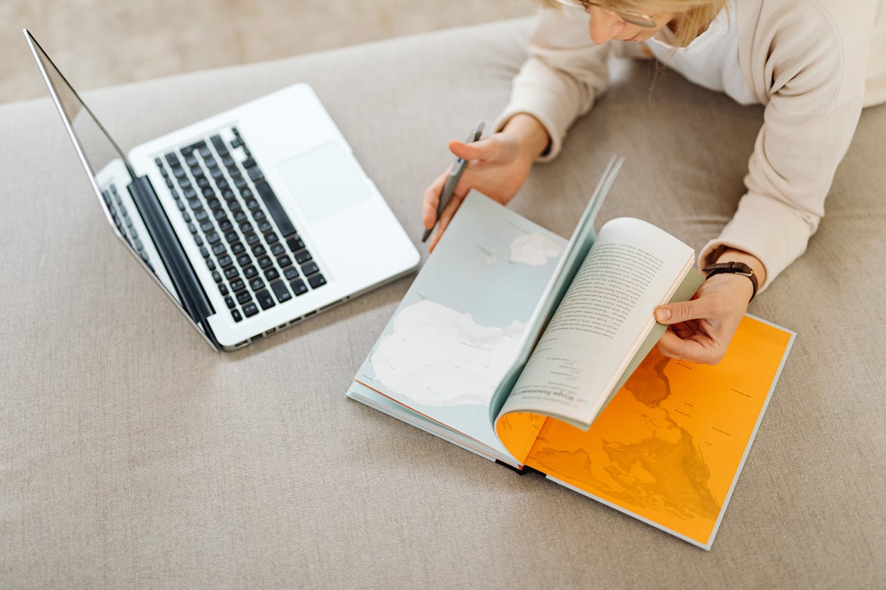 Crafting Captivating Headlines: Your awesome post title goes here Overhead view of a woman using laptop and opening a map book for research.